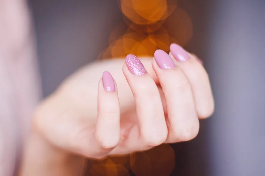 Close up of a finished set of glossy pink glitter nails